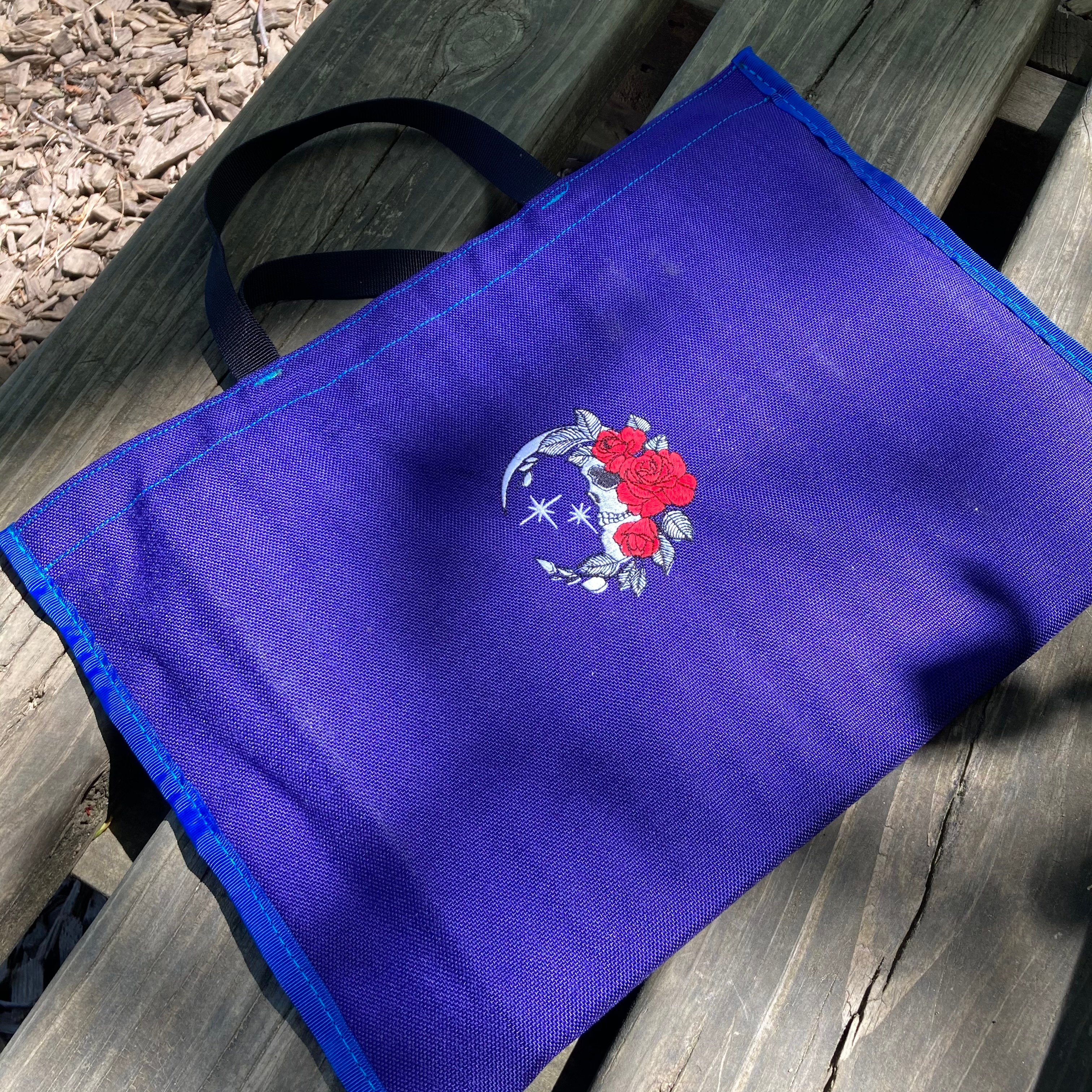 A photo of a custom-embroidered moon-skull with roses on a sitting pad.